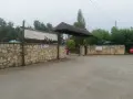 Wjazd na siamoszyce camping przez kamienny mur. Baner "Jura Camp" zaprasza do wypoczynku wśród drzew.
