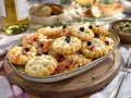 Plate of cookies salés originaux topped with cheese, prosciutto and olives, served with white wine.