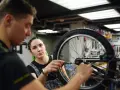 Mechanik rowerowy wyjaśnia, ile kosztuje wymiana dętki w rowerze, podczas gdy kobieta z zielonymi włosami uważnie słucha.