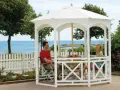 Ett par njuter av utsikten vid havet under en vit paviljong. Perfekt för att bygga paviljong och skapa en avkopplande oas.