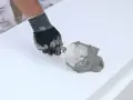 Ręka w rękawicy nakłada zaprawę na styropian. To pokazuje, jaki klej do styropianu wybrać do prac termoizolacyjnych.