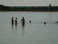 Menschen genießen das naturbad luppa an einem sonnigen Tag. Einige stehen im Wasser, andere schwimmen.