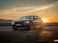 Ciemnoszara limuzyna BMW 330e na parkingu o zachodzie słońca.