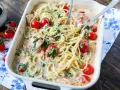 Cremige Lachs Spinat Pasta mit Kirschtomaten in einer Auflaufform, serviert mit zwei Gabeln.