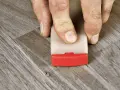 Fingrar använder en kil för att laga laminatgolv.