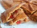 Una deliciosa empanada de carne, cortada en porciones, revela su jugoso relleno de carne deshebrada y pimientos rojos.