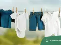 Baby clothes hanging on a clothesline: a blue long-sleeve shirt, a white onesie, blue shorts, and a white romper.