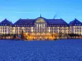 Elegancki Grand Hotel, część sieci luksusowych hoteli, lśni nocą na tle plaży.