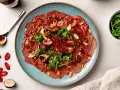 Carpaccio vom Rind mit Pilzen, Rucola und Mandeln, garniert mit Chili und Trüffel. Ein Gericht, das zeigt, was ist Carpaccio.