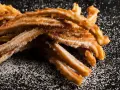 Krispiga churros, pudrade med socker, redo att avnjutas. Ett enkelt churros recept för hemmabruk.