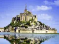 Opactwo Mont Saint-Michel, jeden z najpiękniejszych miejsc we Francji, odbija się w spokojnej wodzie.