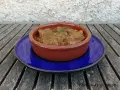 Goulash de ternera humeante en cazuela de barro, servido sobre plato azul. Un plato reconfortante listo para disfrutar.