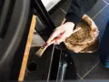 Mano che pulisce la stufa a pellet con un pennello. La manutenzione stufa a pellet ogni quanto è fondamentale per l'efficienza.