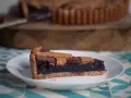Una fetta di crostata al cioccolato, con la sua base dorata e il ripieno scuro e invitante, pronta per essere gustata.