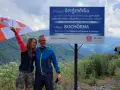 Para, z gruzińską flagą, na tle gór i znaku "Wioska Bochorna", najwyżej położona osada w Europie. Podróżując, warto zapytać: czy w Gruzji jest bezpiecznie?