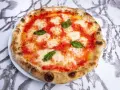 Pyszne ciasto na pizzę neapolitańską z pomidorami, mozzarellą i bazylią, idealne na letni wieczór.
