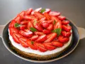 Tarte aux fraises mascarpone, une gourmandise estivale recouverte de fruits rouges frais et de feuilles de menthe.