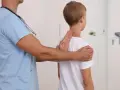 Lekarz bada chłopca, sprawdzając jego postawę. Może to być część diagnostyki zespołu Marfana objawy.