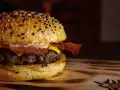 Soczysty burger z bekonem i serem na bułce z sezamem.