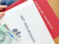 Akt notarialny i polskie banknoty w dłoni.