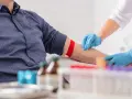 Pielęgniarka w niebieskich rękawiczkach dezynfekuje ramię pacjenta przed pobraniem krwi. Wyniki badań, w tym rdw-sd, będą gotowe wkrótce.