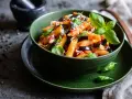 Un plato de pasta alla norma, con penne, berenjena, salsa de tomate y albahaca fresca, espolvoreado con queso rallado.
