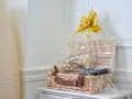 En vacker presentkorg med Ferrero Rocher-choklad och en flaska vin, inslagen i cellofan med en gyllene rosett.