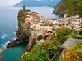 Kolorowe domy Cinque Terre na klifie, idealne na wakacyjne loty do Włoch.