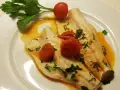 Filetti di branzino in padella con pomodorini e prezzemolo, un piatto leggero e saporito.