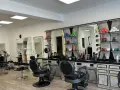 Friseurstuhl und Spiegel in einem modernen Salon mit Regalen voller Kosmetikprodukte.