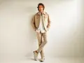 Hombre con ropa business casual en tonos beige: chaqueta, camisa y pantalones.