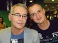 Tomasz Kammel i młody fan pozują do zdjęcia. Tomasz Kammel w szarym garniturze i niebieskiej koszulce, a obok niego młody mężczyzna w czarnej koszulce z napisem "Auckland".