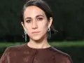 Delfina Delettrez Fendi indossa orecchini pendenti con diamanti e smeraldi, abbinati a un abito marrone con logo Fendi.