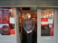 Kobieta w maseczce stoi przed zamkniętym sklepem Vodafone. Informacja na drzwiach głosi, że sklep jest otwarty tylko na odbiór zamówień online, nawet w bank holiday.