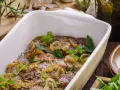 Schab pieczony w piekarniku w naczyniu, duszony z cebulą i ziołami. Aromatyczne danie gotowe do podania.