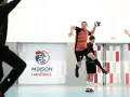 Piłkarz ręczny, niczym szczypiornista, wyskakuje do rzutu. W tle logo "Maison du Handball".