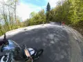 Motocyklista pokonuje krętą drogę stu zakrętów, otoczoną zielonym lasem.