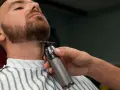 Barbero perfilando la barba ancla de un cliente con una recortadora.