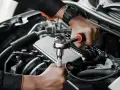 Mechanik wykonuje wymiana pompy paliwa krok po kroku, używając klucza nasadowego do odkręcenia śrub w silniku samochodu.