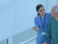 Enfermera sonriente ayuda a un anciano a caminar. El **fp tcae** de la atención médica se refleja en su mirada.