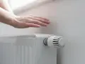 Dłoń nad grzejnikiem, sprawdzająca ciepło. Rozpoczyna się sezon grzewczy, czas na komfortowe ogrzewanie.
