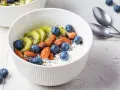 Schüssel mit Magerquark, Blaubeeren, Kiwi, Mandeln und Chiasamen. Perfekt für gesunde Magerquark Rezepte.