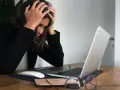 Femme stressée devant son ordinateur, les mains sur la tête, face à une saisie administrative à tiers détenteur.