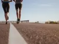 Coppia corre su strada asfaltata, godendosi la libertà e la velocità media corsa sotto un cielo azzurro.