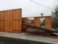 Drewniana wiata w budowie, z widocznymi elementami konstrukcji i bramą.