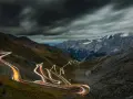 Ślady świateł samochodów wiją się serpentynami na stromych zboczach górskich, tworząc świetlisty szlak na przełęczy Stelvio.