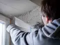 Hand mit Handschuh legt Armierungsgewebe an, um die Fensterlaibung zu verputzen.