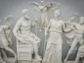 A frieze depicting ancient pagan gods and goddesses, with Zeus seated and Athena standing, surrounded by winged figures and warriors.