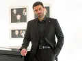 Uomo elegante in completo nero, camicia nera uomo abbinamento perfetto. Sfondo con quadri di busti classici.