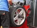 Meccanico effettua la bilanciatura gomme su un'auto sportiva. L'operazione garantisce una guida fluida e sicura.